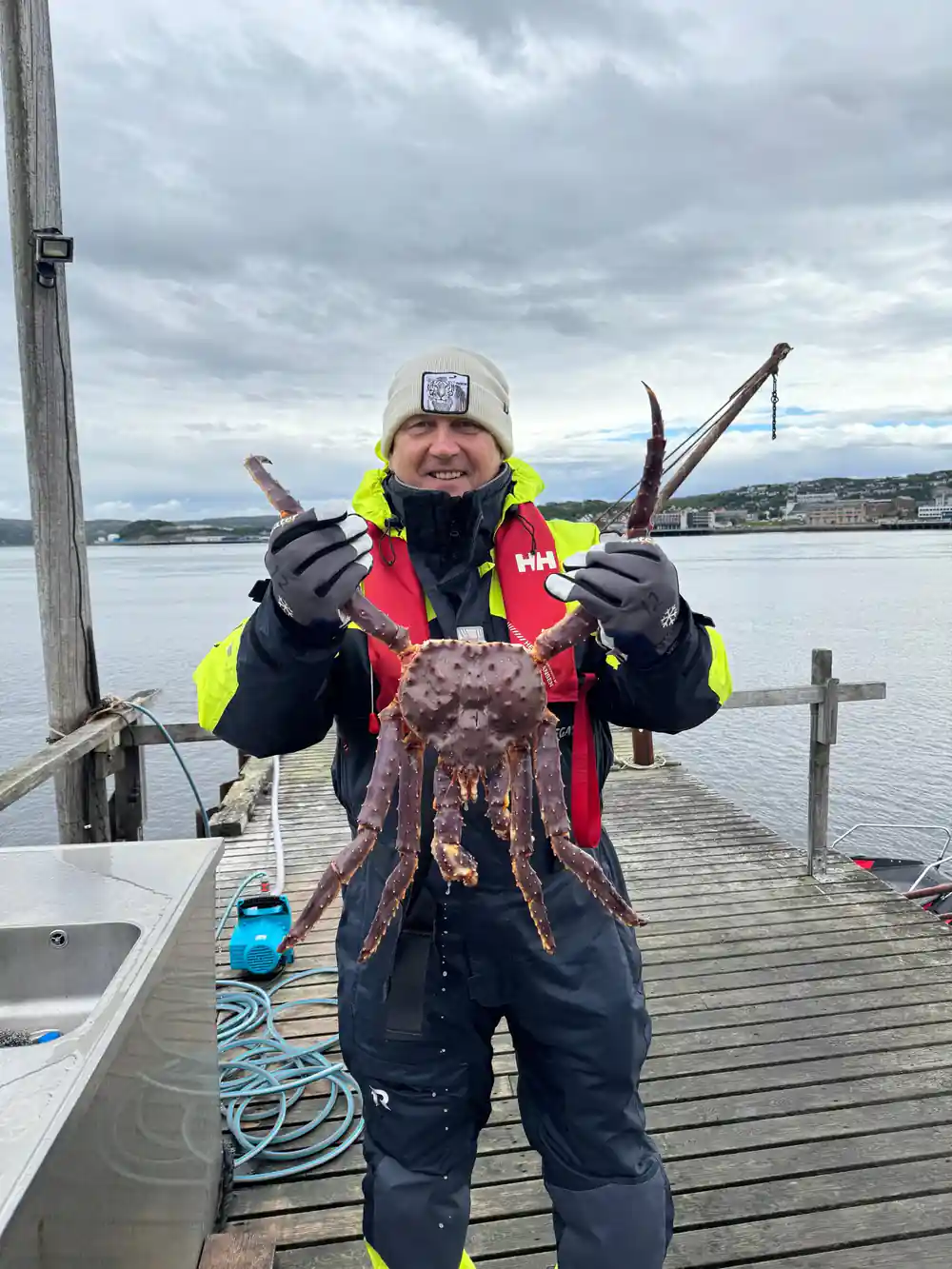 Crew member on the pier holding a large king crab out