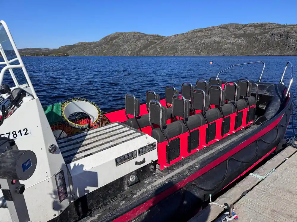 The empty red RIB moored with its seats and a crab pot aboard