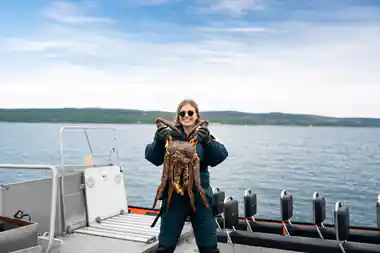 Guest on the RIB holding a king crab up with both gloved hands