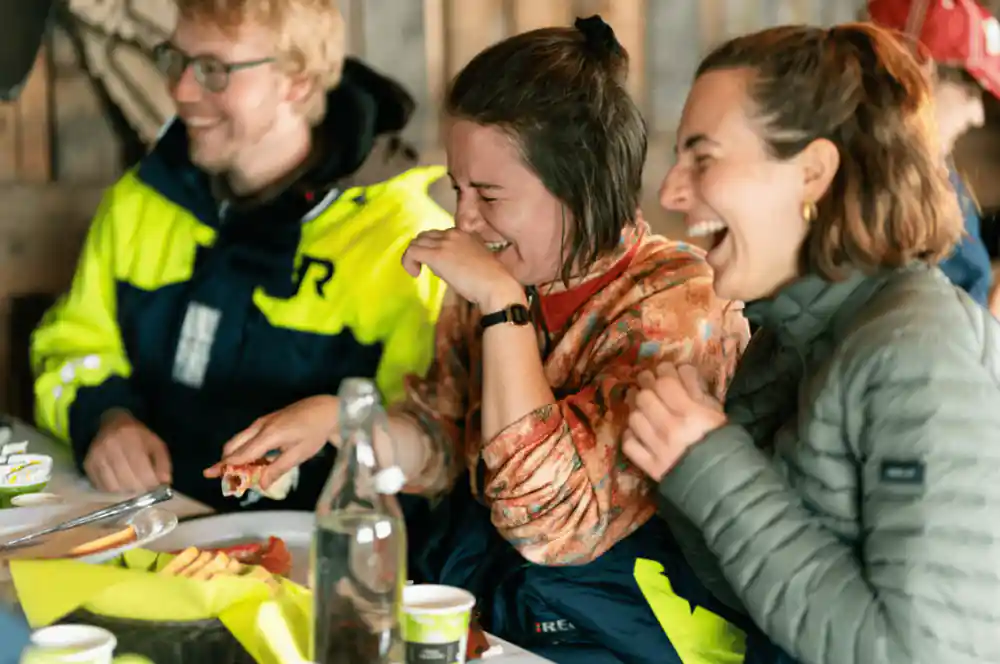 Guests in flotation suits laughing together over the crab meal