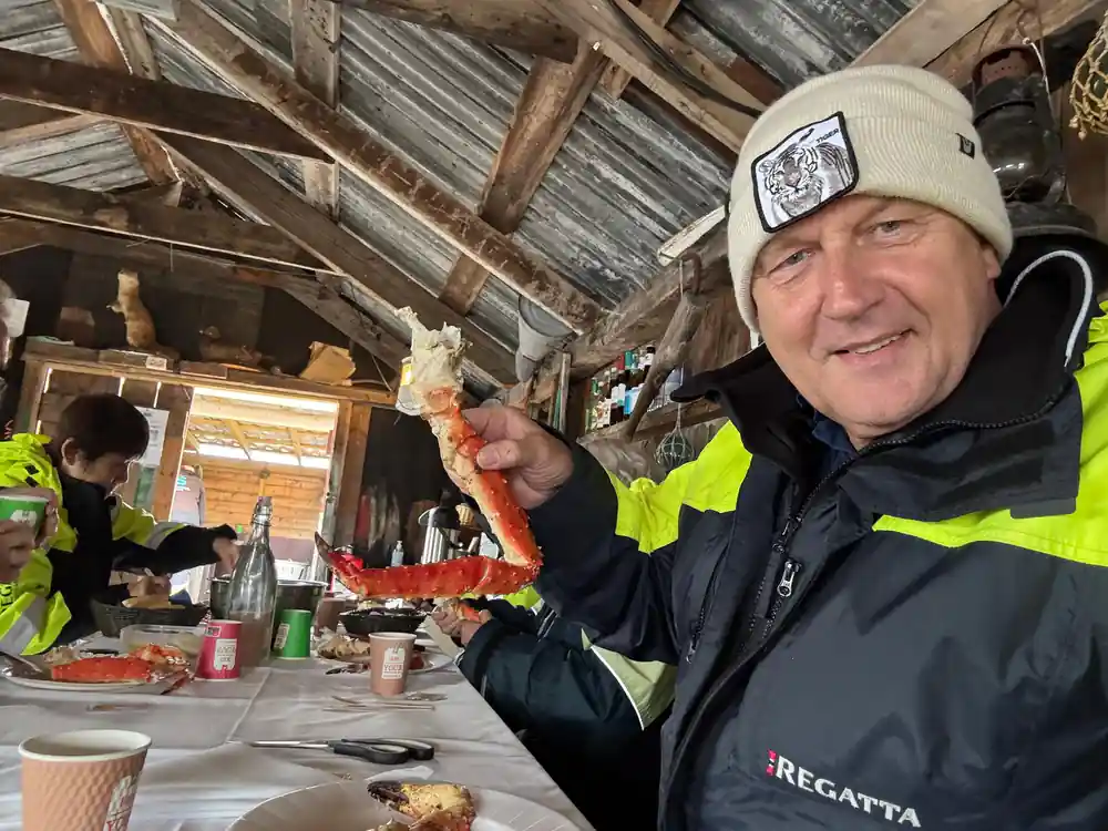 Guide inside the wooden boathouse holding up a crab leg
