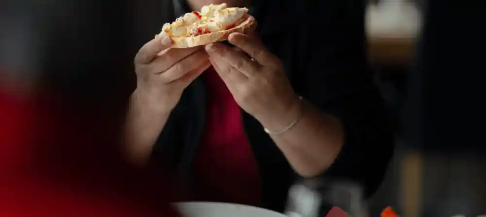 Hands holding a piece of crab meat on bread