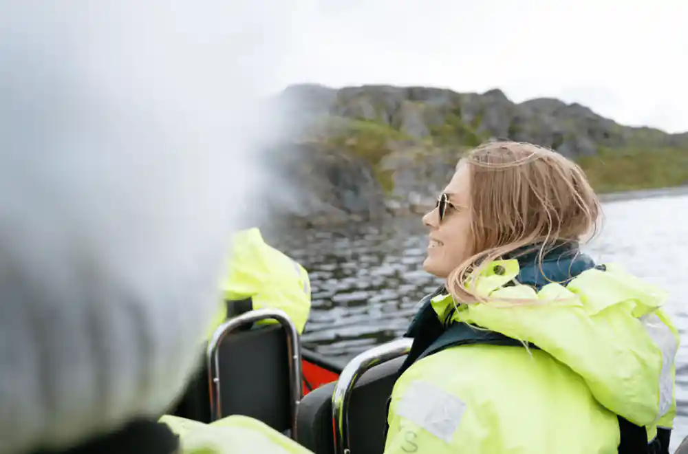 A passenger in a yellow flotation suit watching the shoreline